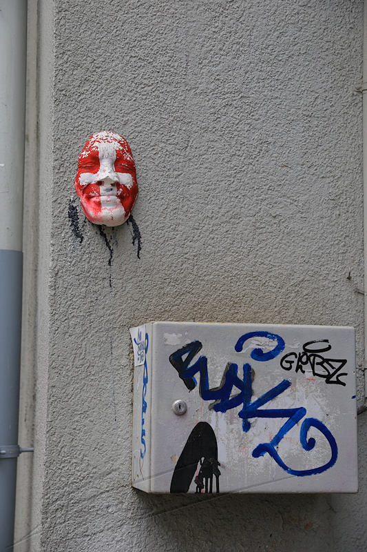 divers graffiti tag visage plâtre genève geneva suisse swiss déprédation sale art de rue débile street art visage sculpture humain croix blanche fond rouge red white cross mur wall